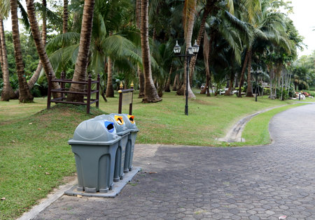Gray plastic bins row beside walkway in public park in Thailand.の写真素材