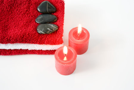 Tower of red and white towels, stones and burning red candles on a white backgroundの写真素材