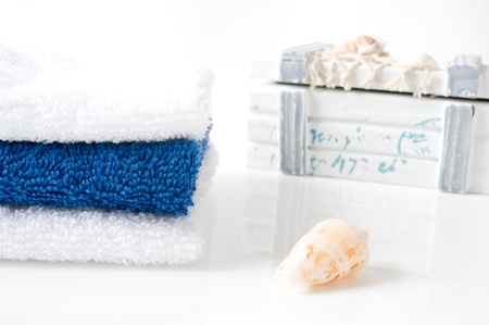 A tower of blue and white towels, seashells and a pirate chest on a white backgroundの写真素材