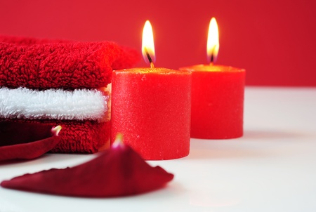 A tower of white and red towels, rose petals and lit red candlesの写真素材
