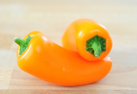 two sweet orange peppers on a wooden tableの写真素材