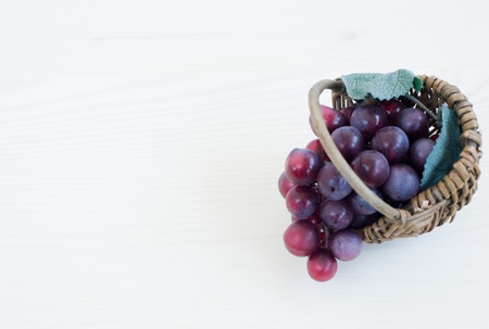 brush of dark grapes in a basket on a wooden tableの写真素材