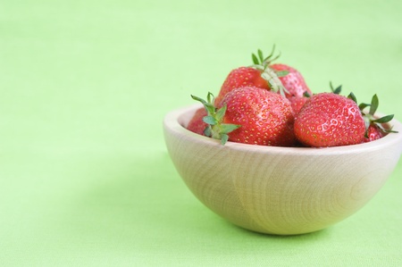 Fresh strawberries in a wooden bowl on a green napkinの写真素材