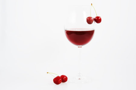 Red wine in glass with cherries on a white backgroundの写真素材