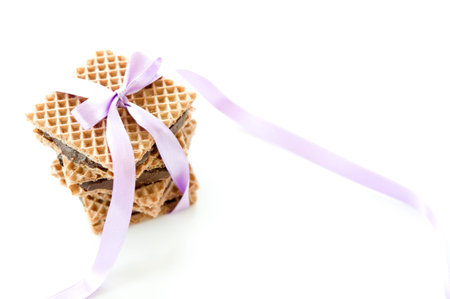 Square waffle with chocolate and nut filling, tied with purple ribbon on a white backgroundの写真素材