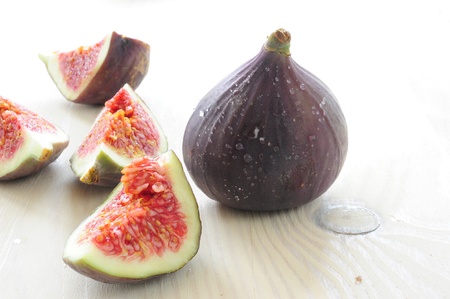 sliced ââfigs and figs with the drops on a wooden tableの写真素材