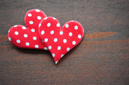 Two red heart made ââof cloth on a dark wooden tableの写真素材