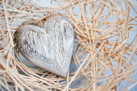 Vintage wooden heart in a nest of straw on a wooden tableの写真素材