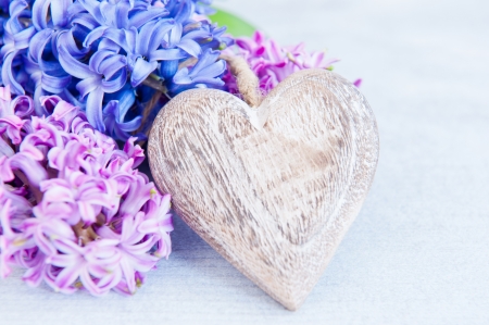 Pink and purple hyacinths with a wooden heart on a white tableの写真素材