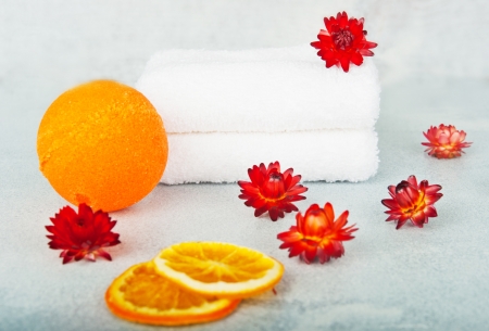 Two white terry towels, decorated with orange flowers, orange ball next to the bath, in the foreground dried orange segmentsの写真素材