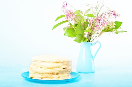 homemade layer cake on a blue plate, the background blue jar with a bouquetの写真素材