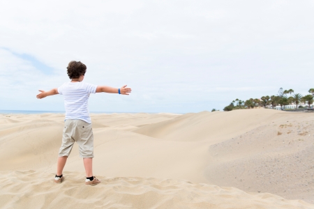 European boy stands on the sandy bottom of the outstretched handsの写真素材