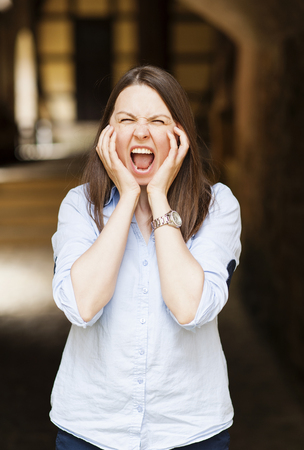 Young brunette woman stressfull holding hands on head terrified in panic frustratedの写真素材