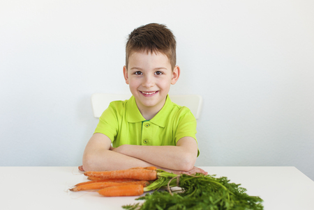Closeup of adorable young boy with carrot. White background.の写真素材