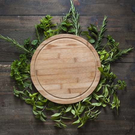 empty wooden cutting board with frame of freesh leafsの写真素材