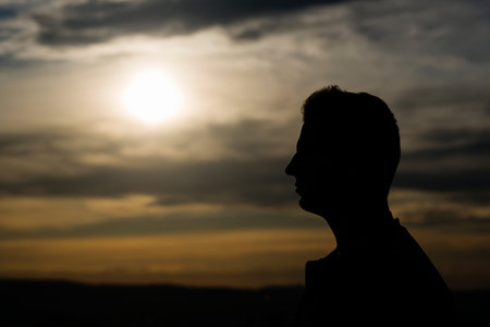 Silhouette of a young handsome man at sunset. Closeup