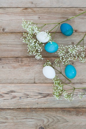 Delicate spring flowers with Easter bright eggs on a wooden tabletop. Space for textの写真素材