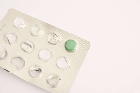 Green pills in metallic blister. Close-up. Isolated on white backgroundの写真素材