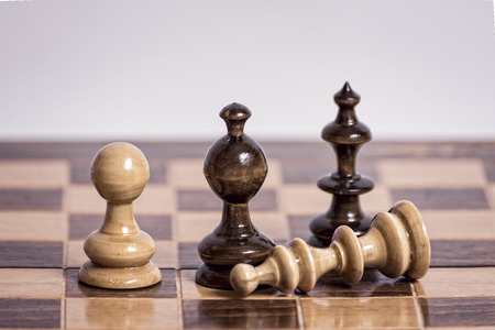 Old wooden chess pieces on a chessboardの写真素材