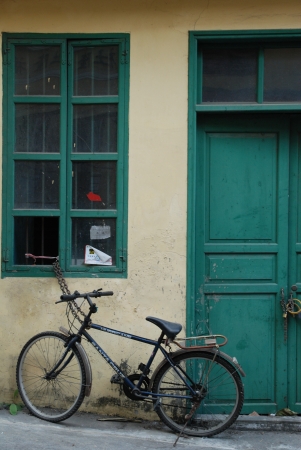 An old bicycle in front of the green doorの写真素材