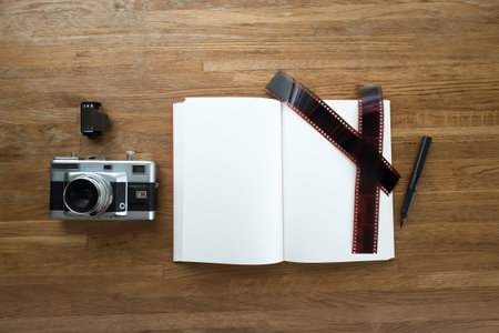 35mm film camera, notebook, pen, film strip and film roll lay on wooden table, view from top with CopySpaceの写真素材
