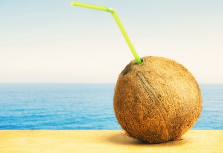 Coconut with drinking straw on a beach at the caribbean sea の写真素材