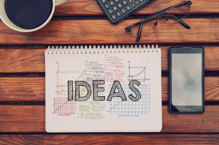 Notebook with text Ideas inside on table with coffeeの写真素材