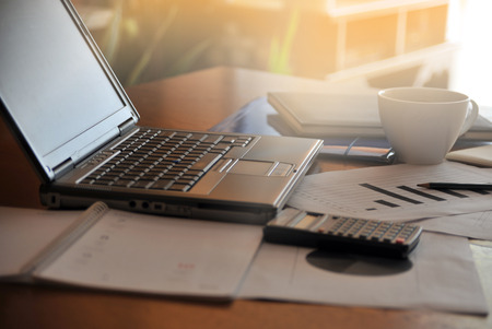 Workplace with open laptop with black screen and business documents with charts growth and pen.- workplaceの写真素材