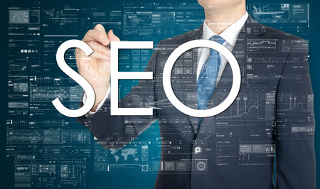 the businessman is writing SEO on the transparent board with some diagrams and infochartsの写真素材