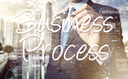 businessman writes on board text: Business Process - with sunset over the city in the background, the visible sun's rays in a picture are symbolizing the positive attitudeの写真素材