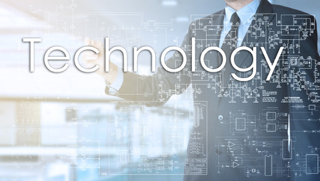 the businessman in the office is writing on the transparent board: Technologyの写真素材