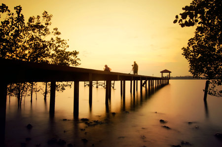 silhouette of a photographer on the jetty during sunsetの写真素材