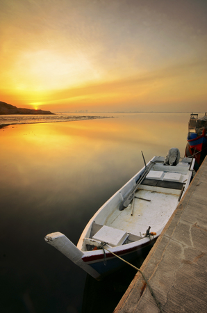 Fishing boat on the beach on sunset timeの写真素材