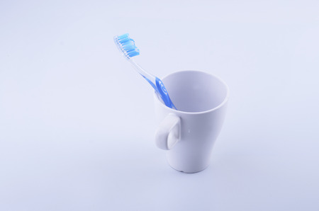 Close up white ceramic coffee cupwith blue tooth brush on white backgroundの写真素材
