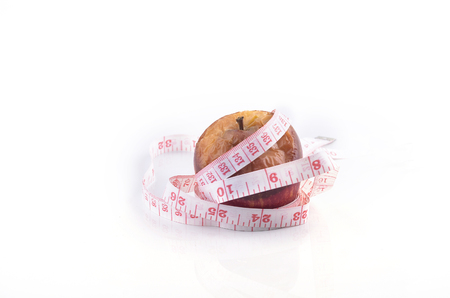 Wilted rotten apple and measuring tape on white background. Diet conceptの写真素材