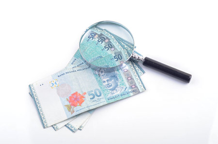 Magnifier glass and money on white background. Financial concept.