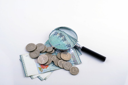 Magnifier glass and coin on white background. Financial concept.の写真素材