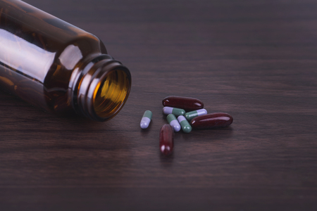Pill bottle with various pills and capsules on wooden backgroundの写真素材