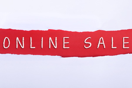 Torn paper with a ONLINE SALE word on red background.の写真素材