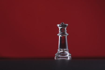 Solitary black chess piece in genuine ebony wood in focus standing on a glossy table in the darkの写真素材