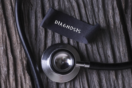 DIAGNOSIS word written on label tag with Stethoscope on wood backgroundの写真素材