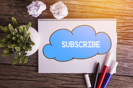 SUBSCRIBE word with Notepad and green plant on wooden backgroundの写真素材