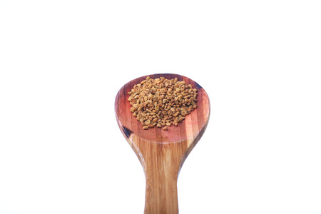 Fenugreek seeds on a brass spoon isolated on a white backgroundの写真素材