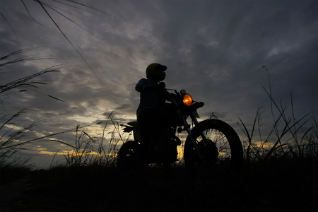 Silhouette of a man riding his motorcycle during sunsetの写真素材
