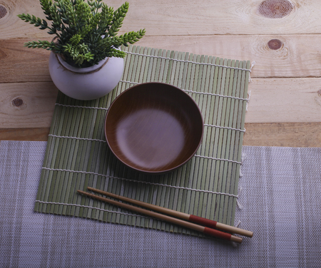 Wooden bowl and a pair of chopstick on bamboo backgroundの写真素材