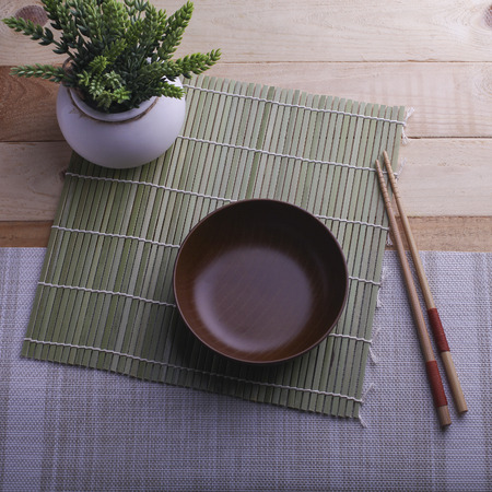 Wooden bowl and a pair of chopstick on bamboo backgroundの写真素材