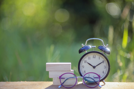 Black alarm clock stacked on wooden bar with shallow DOF green backgroundの写真素材