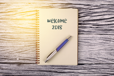 Welcome 2018 word on notepad with wooden backgroundの写真素材