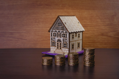 House rental and mortage business concept with cardboard house model with heap of coin money on wooden floorの写真素材