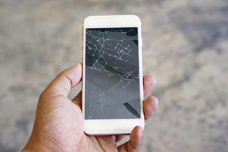 Businessman holding a crack smartphone. Shallow DOFの写真素材